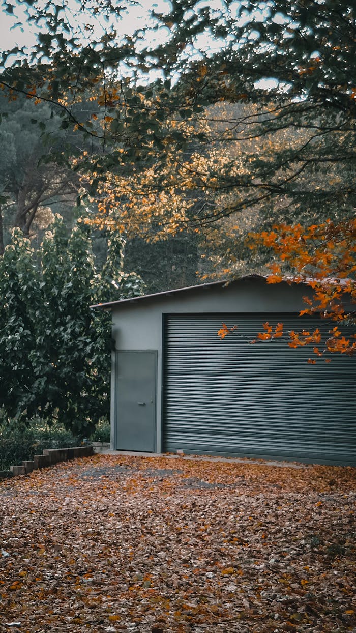 A serene garage surrounded by autumn foliage and fallen leaves in a quiet outdoor setting.