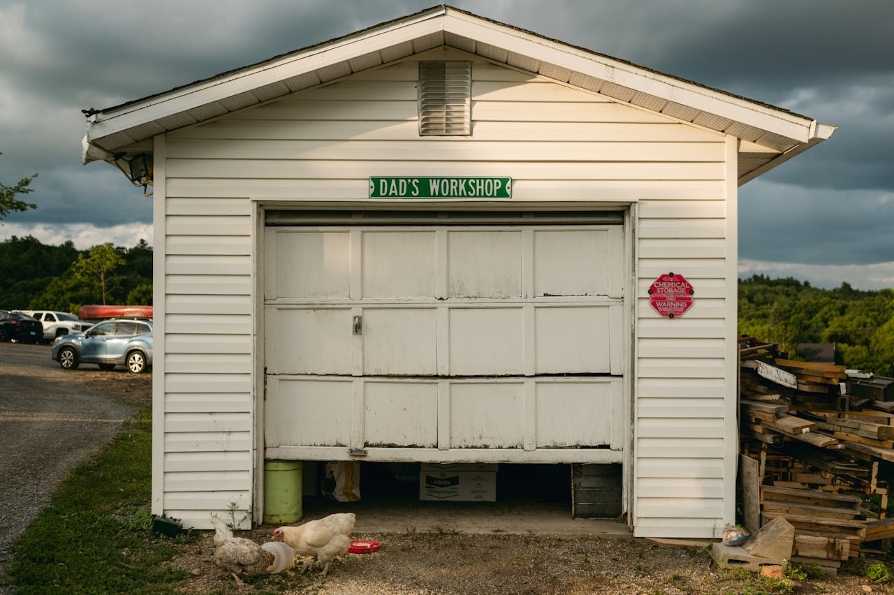 A quaint garage workshop labeled 'Dad's Workshop' surrounded by nature and chickens.